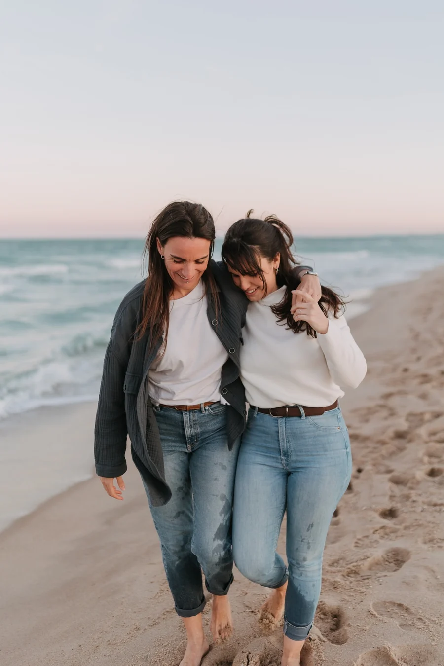 La pareja camina abrazada por la playa