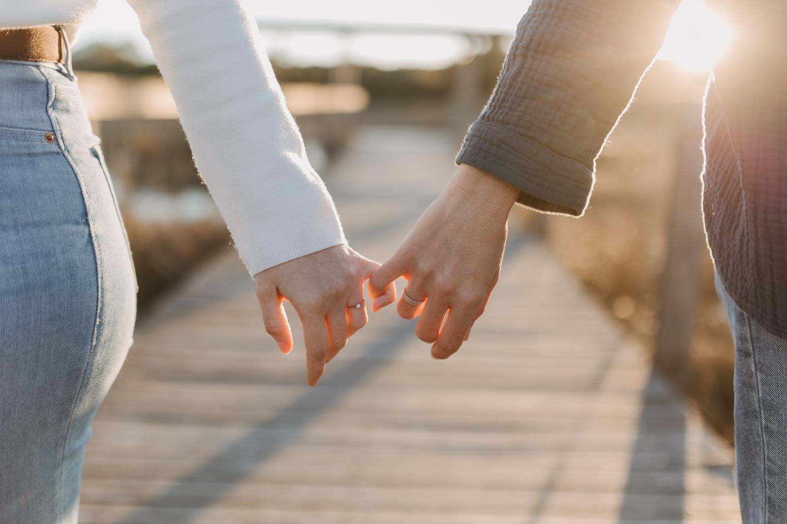 Las manos de las novias se encuentran al atardecer